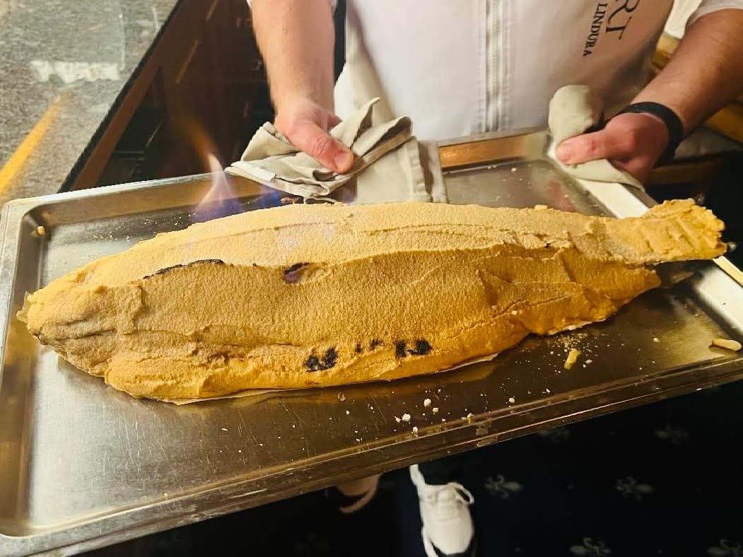 Franco Lindura tranchiert einen im Salzteig gebackenen Fisch am Tisch