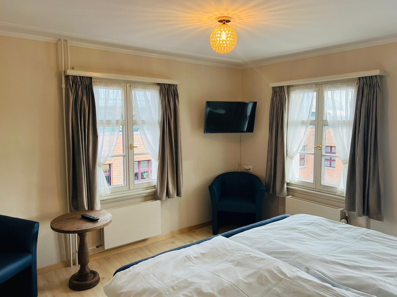 Hotelzimmer mit Sessel, Wand-TV und zwei Fenstern im Gasthaus Rössli Wil