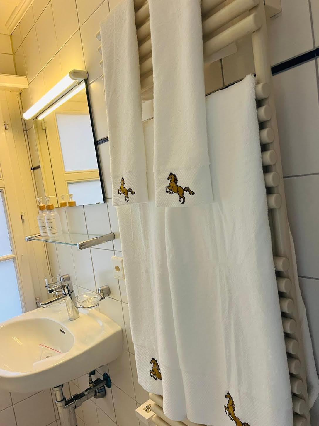 Weisse Frotteetücher mit gesticktem goldenem Rössli im Badezimmer